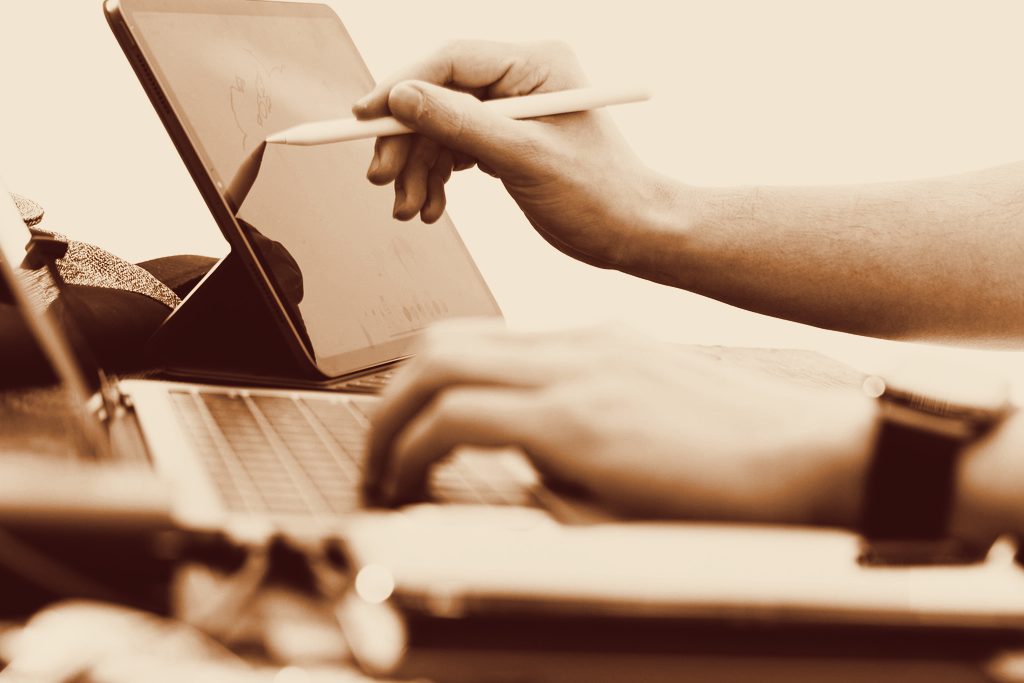 Hands working on a laptop and tablet